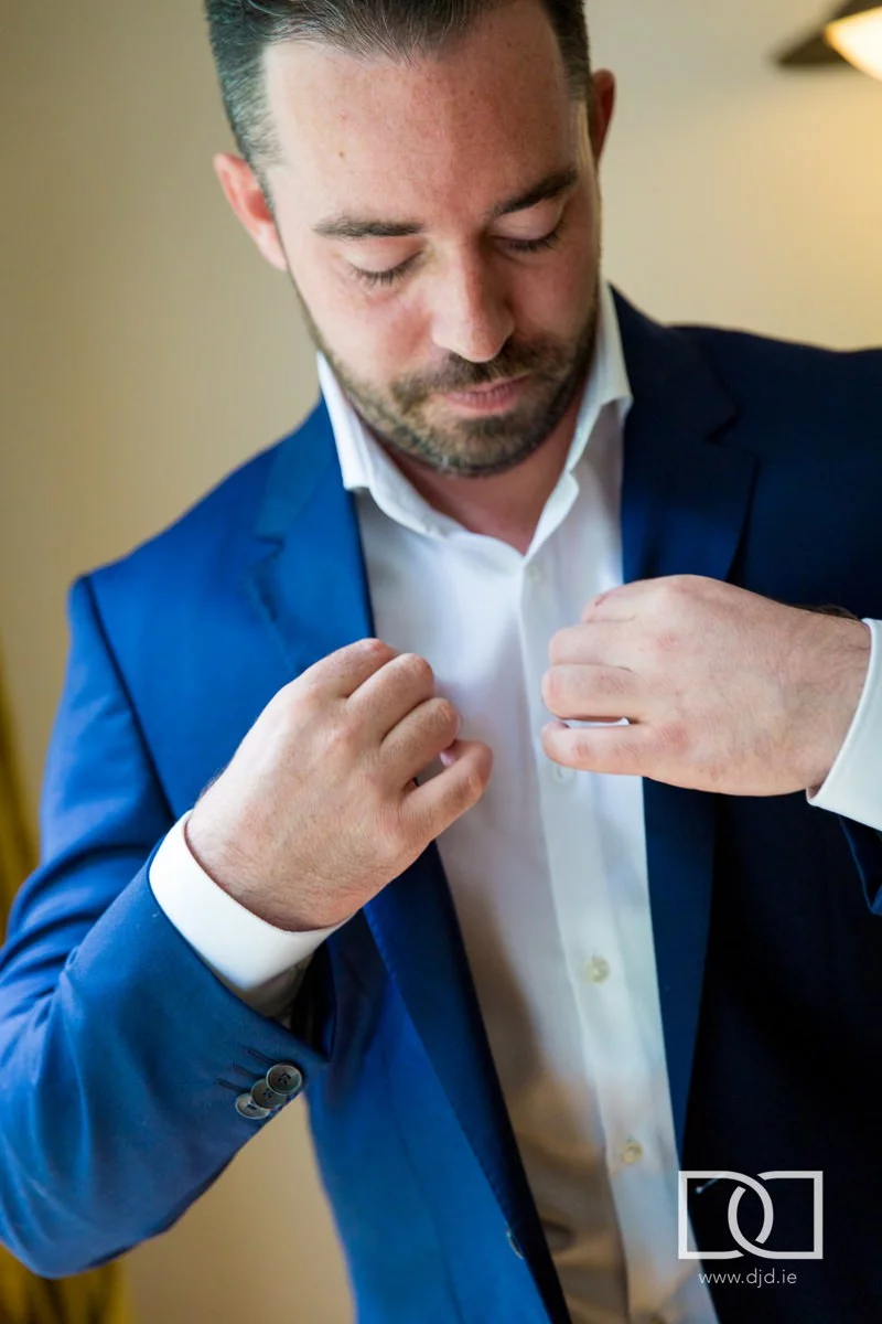 groom putting on his jacket at his wedding at castle leslie co monaghan