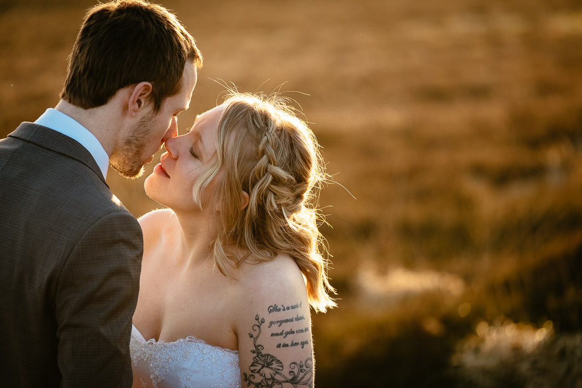 bride and groom kissing on a mountain at sunset