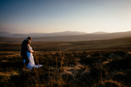 engaged couple at top of mountain in lreland watching the sun set