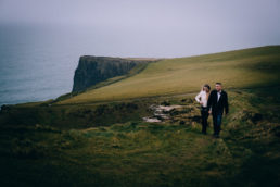 engaged couple walking through a field