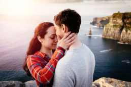 guy and girl hugging at the top of a cliff at sunset