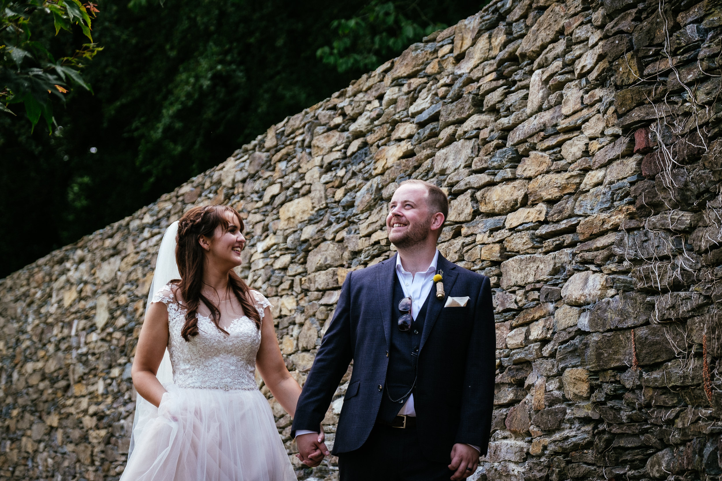 bride and groom strolling by a wall in ballybeg house