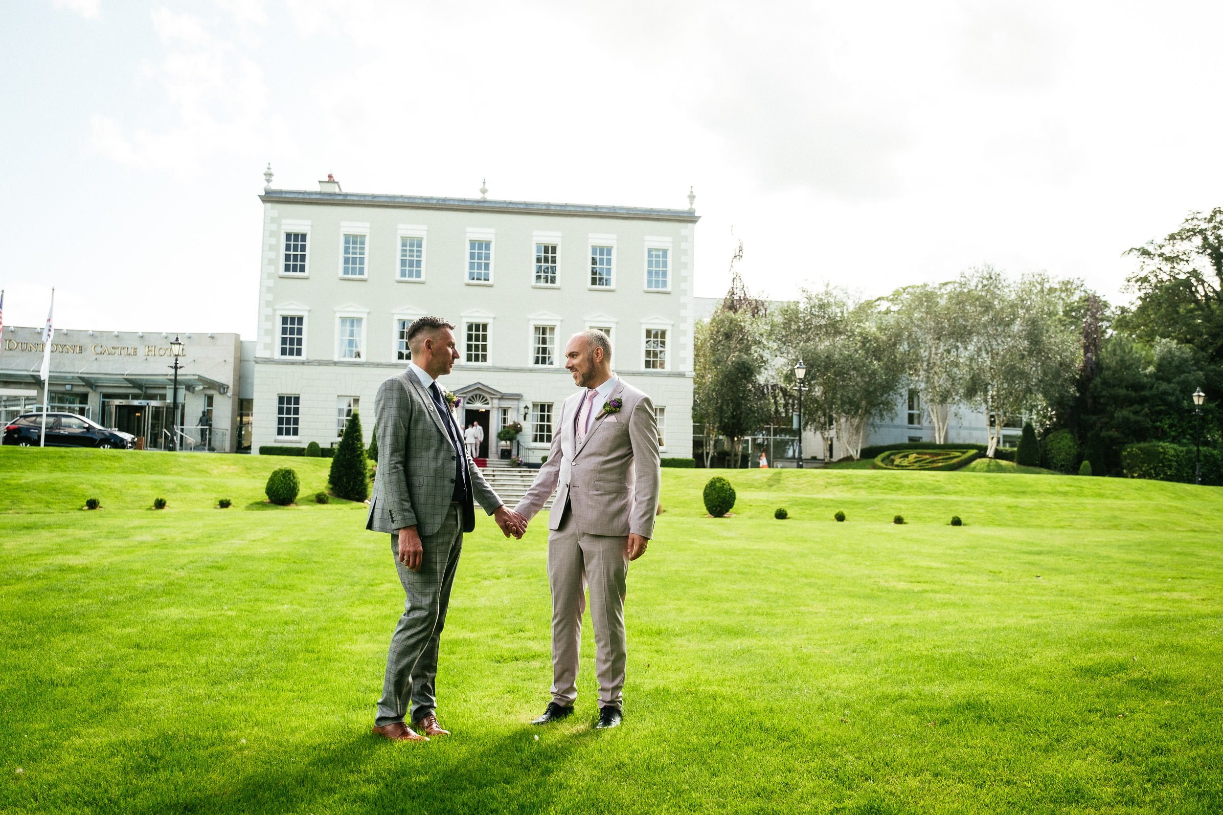 two gay grooms holding hands and chatting in front of dunboyne castle