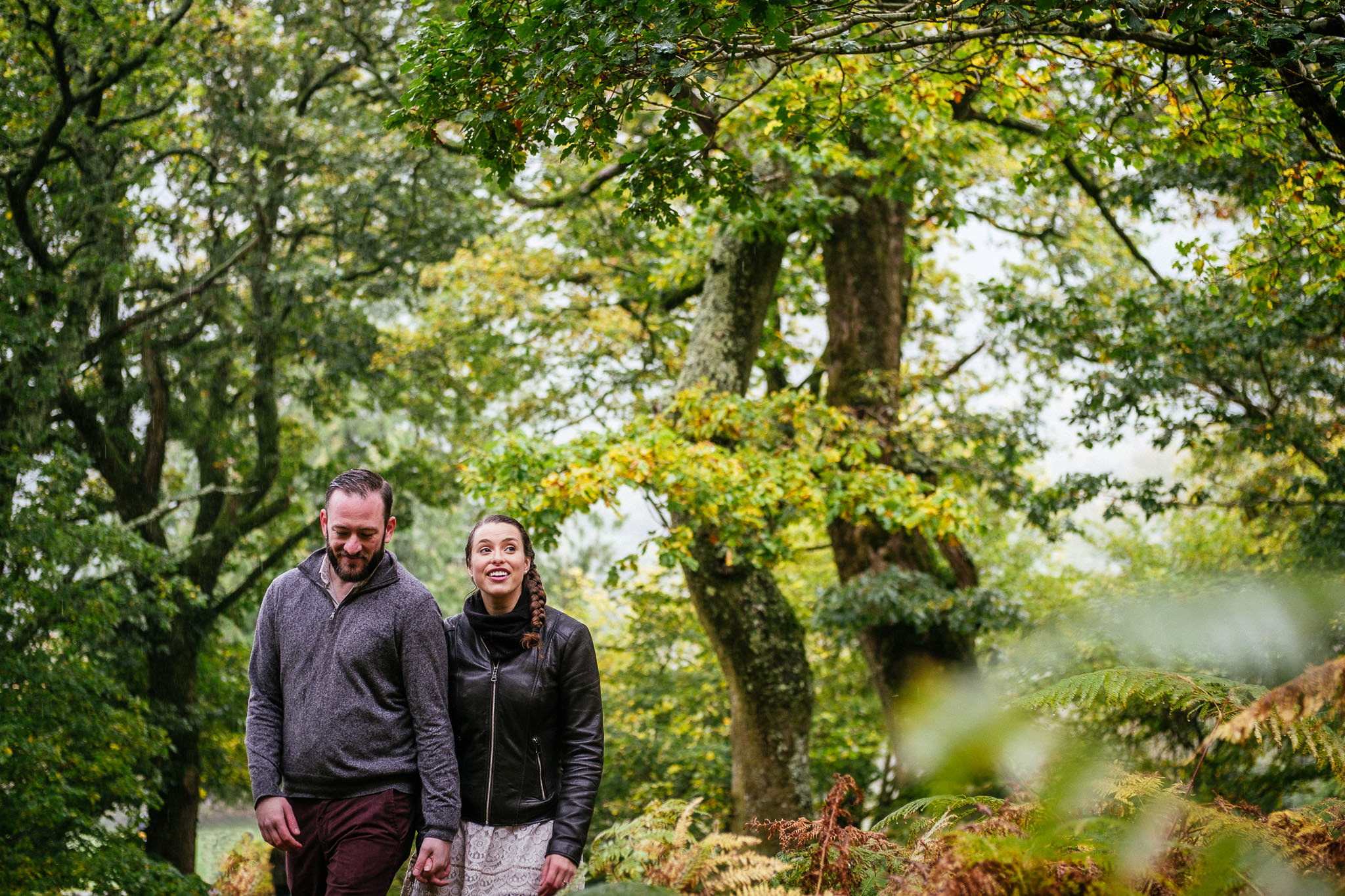 engaged couple walking through a forrest in the rain in Ireland