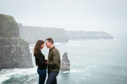 engaged couple embracing at the Cliffs of Moher Ireland